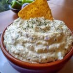 Creamy jalapeño dip in white bowl with tortilla chips