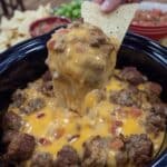 Rotel Dip With Sausage bubbling in crock pot with tortilla chips