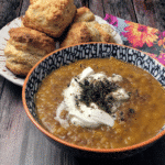 Vegetarian Lentil Soup 7 A table setting with a bowl of lentil soup, crusty bread, and a side salad.