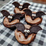 Oreo Bats 7 Close-up of three Oreo bats arranged on a parchment-lined baking sheet.