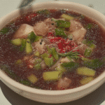A steaming bowl of Beef Noodle Soup garnished with fresh herbs.