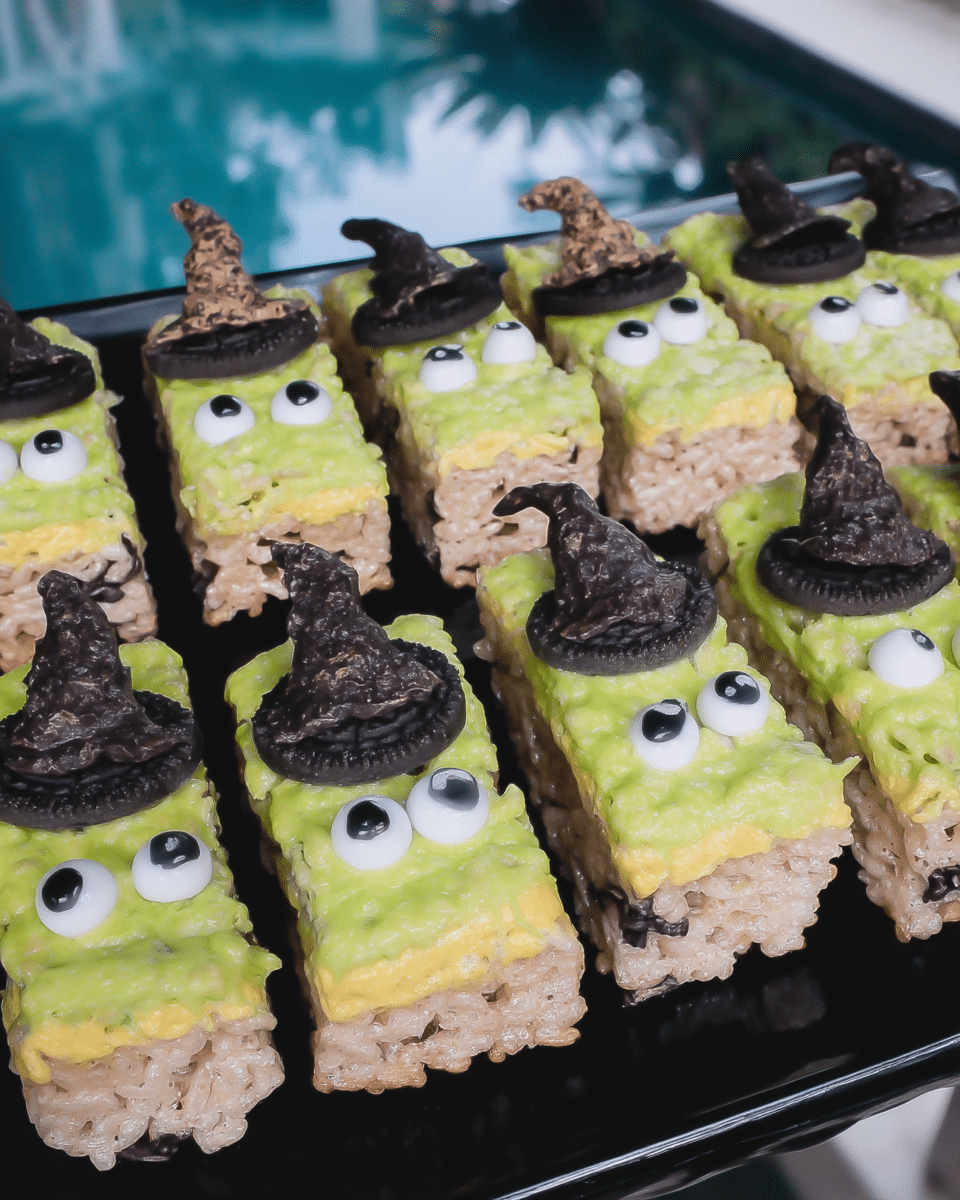 Witch Halloween Rice Krispie Treats 9 A hand dipping a rice krispie treat into melted green candy melts.