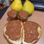 Crockpot pear butter in canning jars on a farmhouse counter