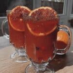 Cranberry orange cider in a mug with cinnamon stick and orange slice