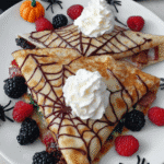 Spiderweb Crepes 7 Stack of spiderweb crepes with chocolate sauce, whipped cream, and berries.