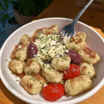 A close-up view of the finished Air Fryer Pumpkin Gnocchi Bake, highlighting the golden brown cheese and crispy sage.
