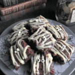 A hand holding a spatula, mixing brownie batter in a bowl.