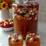 A glass of Caramel Apple Punch garnished with apple slices and cranberries.