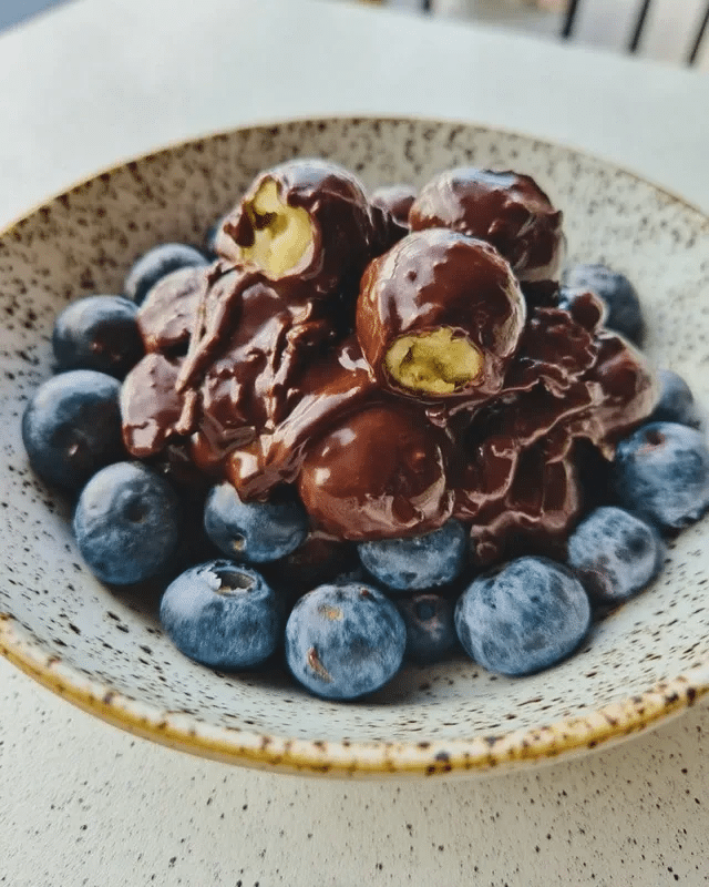 Dark Chocolate Covered Blueberries 9 A bowl of dark chocolate covered blueberries with a spoon.