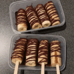 A platter of Frozen Chocolate Covered Banana Pops served with other frozen treats, such as fruit skewers and small ice cream cones.
