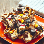 Halloween Candy Bark 7 Halloween Candy Bark served in a bowl with a scoop and a few pieces scattered around.