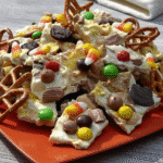 Close-up of colorful Halloween Candy Bark broken into pieces on a parchment-lined baking sheet.