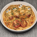 Plump Italian sausages wrapped in bucatini pasta, resembling mummies, served on a plate with marinara sauce.