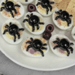 A platter of Spider Deviled Eggs garnished with fresh herbs.