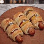 Close-up of mummy hot dogs on a baking sheet, ready to be enjoyed.