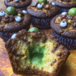 Close-up of Witch Cauldron Brownie Bites on a platter, decorated with green frosting, sprinkles, and pretzel stick handles.