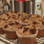 Close-up of a paleo pumpkin chocolate chip muffin with a bite taken out of it, showing the soft, fluffy texture and the melty chocolate chips.