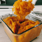 A whole pumpkin and a halved pumpkin showcasing the vibrant orange flesh and seeds inside.